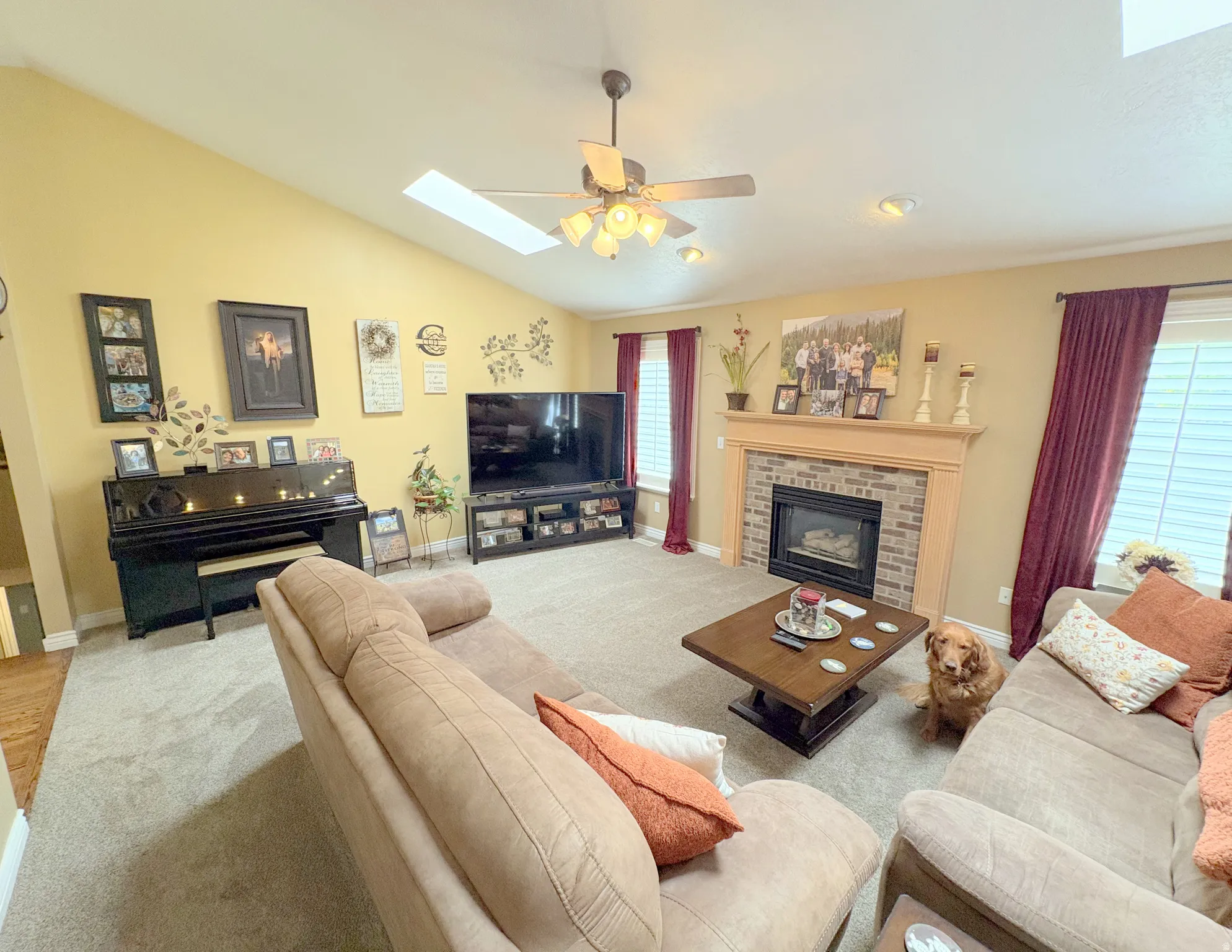 Living area featuring a vaulted ceiling with skylight, recessed lighting, and a ceiling fan