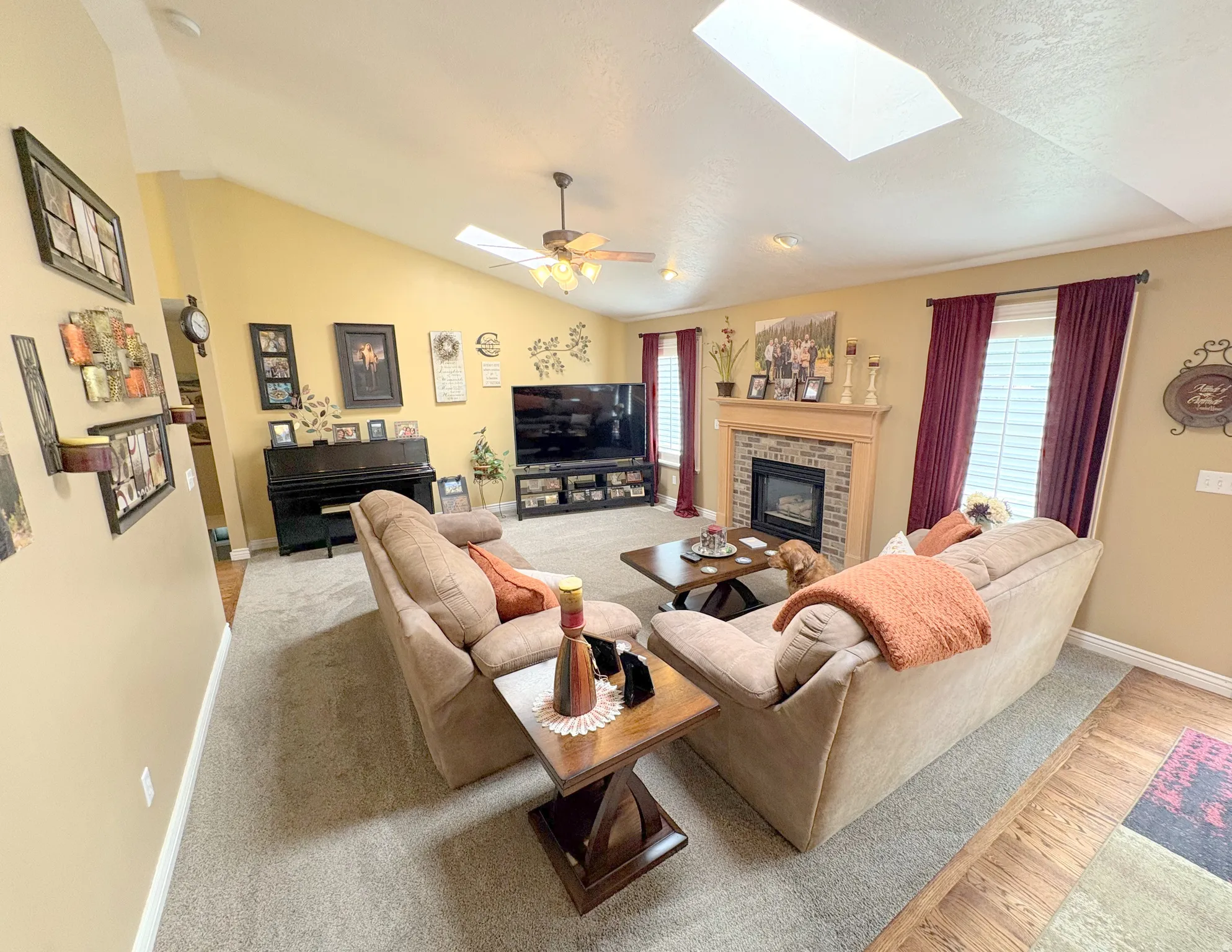 Spacious living area featuring a vaulted ceiling with skylights, a ceiling fan, and recessed lighting