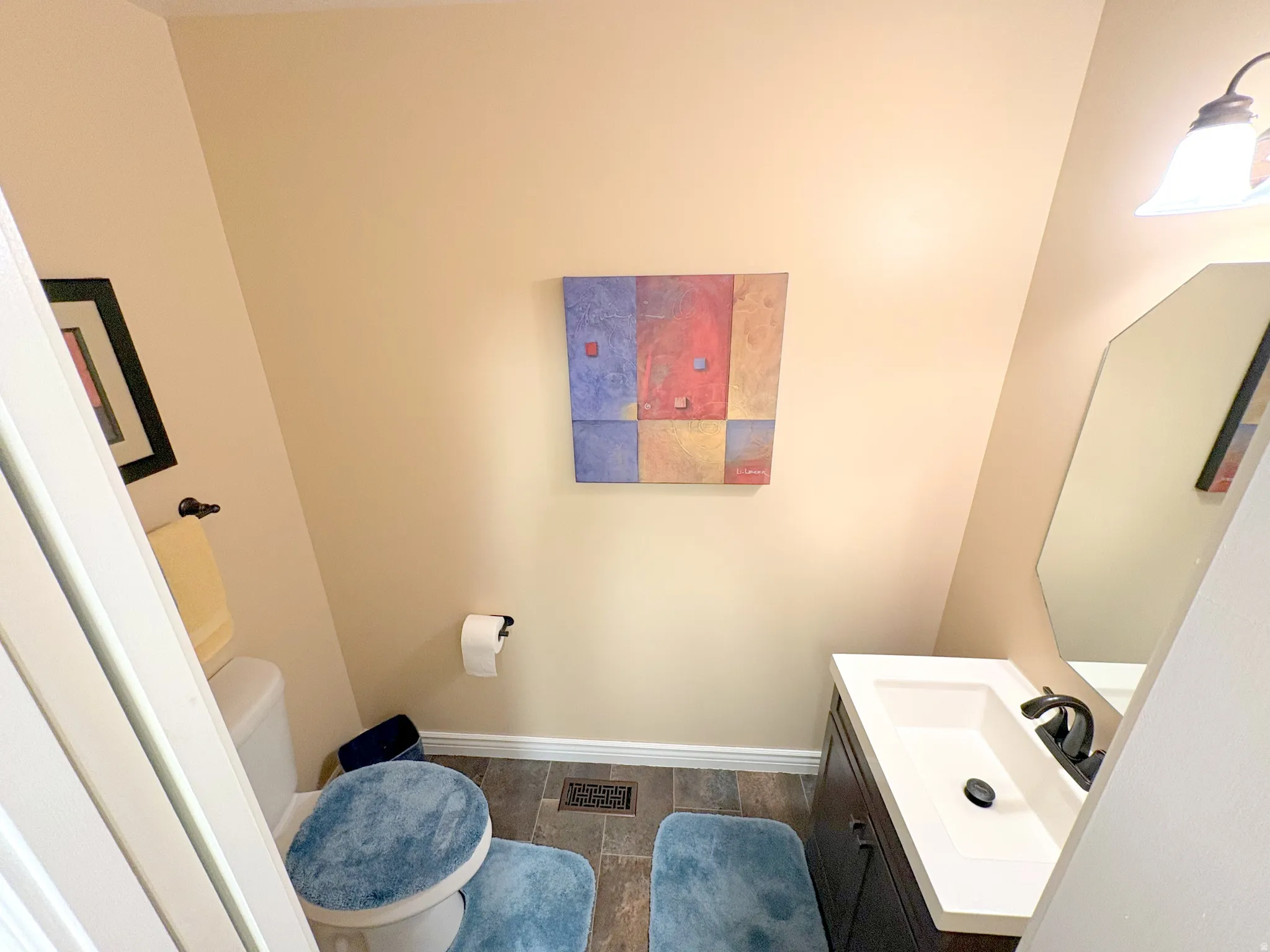 Compact powder room featuring a single vanity with a white countertop and dark base, accented by a black faucet and an octagonal mirror