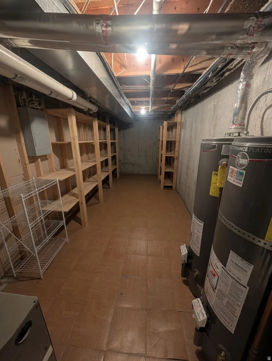 Lower level utility room featuring two water heaters, exposed ceiling joists, and concrete walls