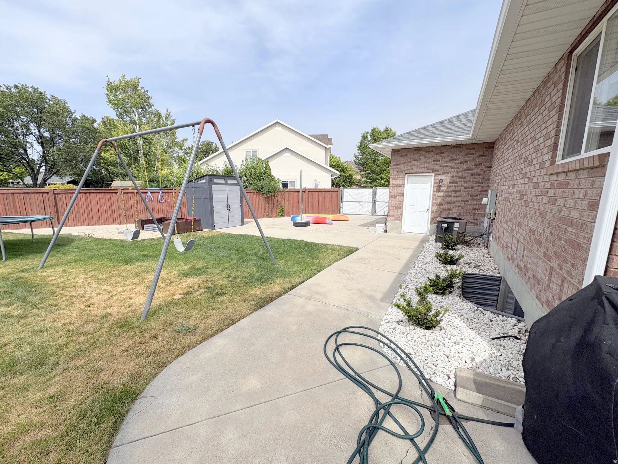 Spacious backyard featuring a concrete patio, red brick exterior, and a manicured lawn