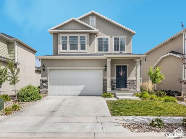 Two-story stucco facade featuring a two-car garage, stone accents, and a covered entry