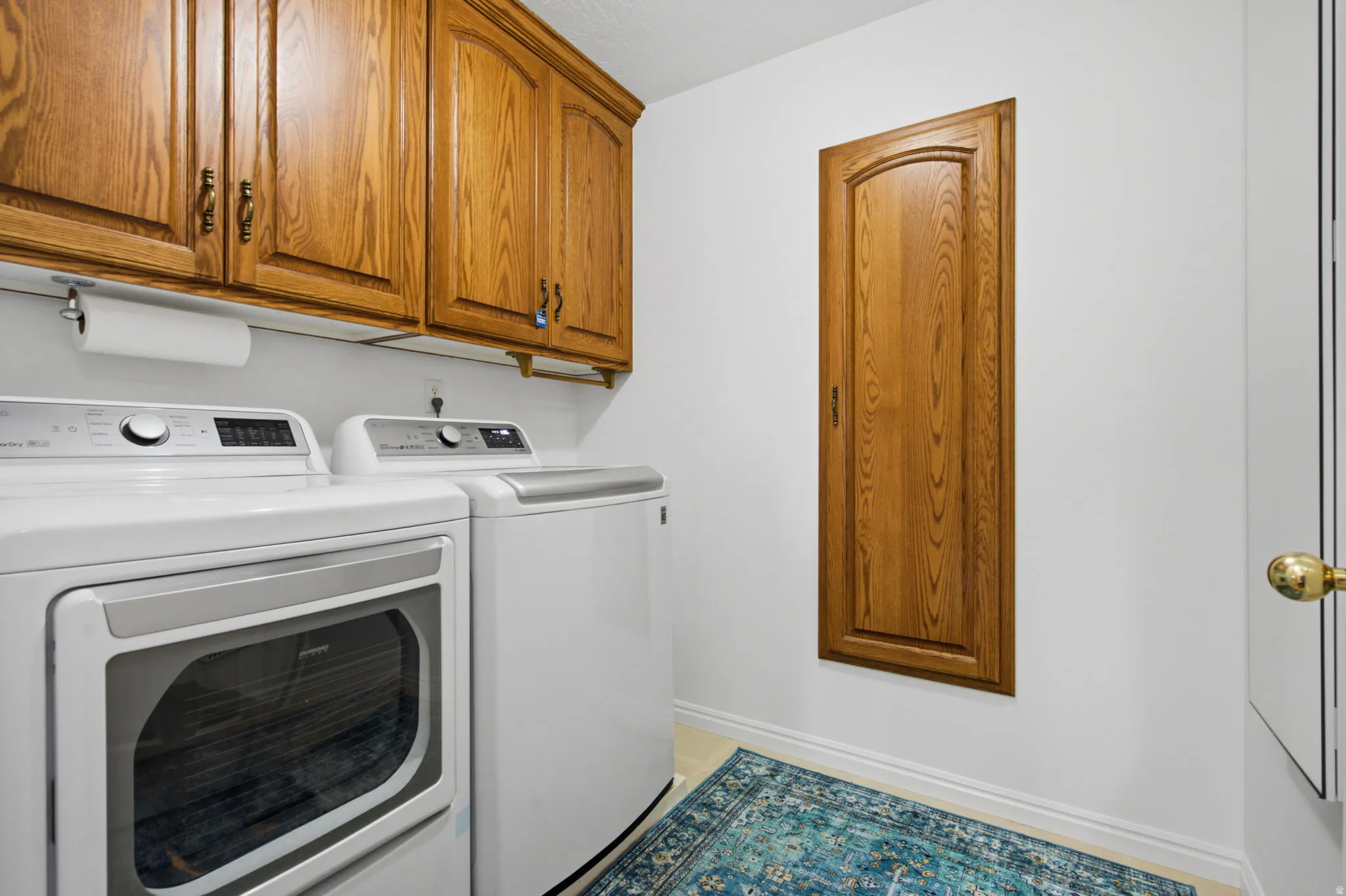 Laundry area featuring wood cabinetry, light-toned flooring, and an integrated wood-paneled utility door