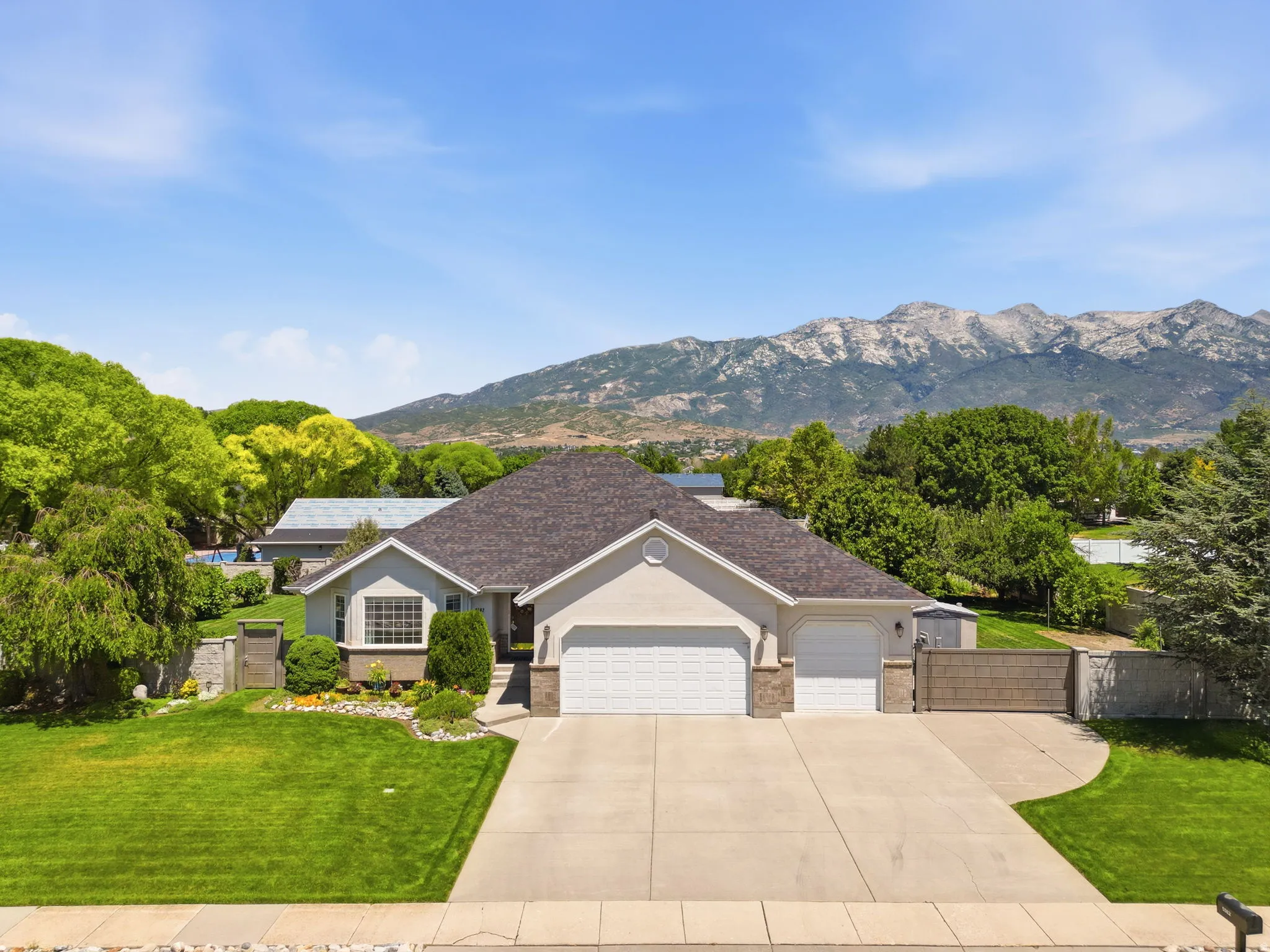 Contemporary residence featuring a light-colored stucco exterior with stone accents and a prominent shingled roof