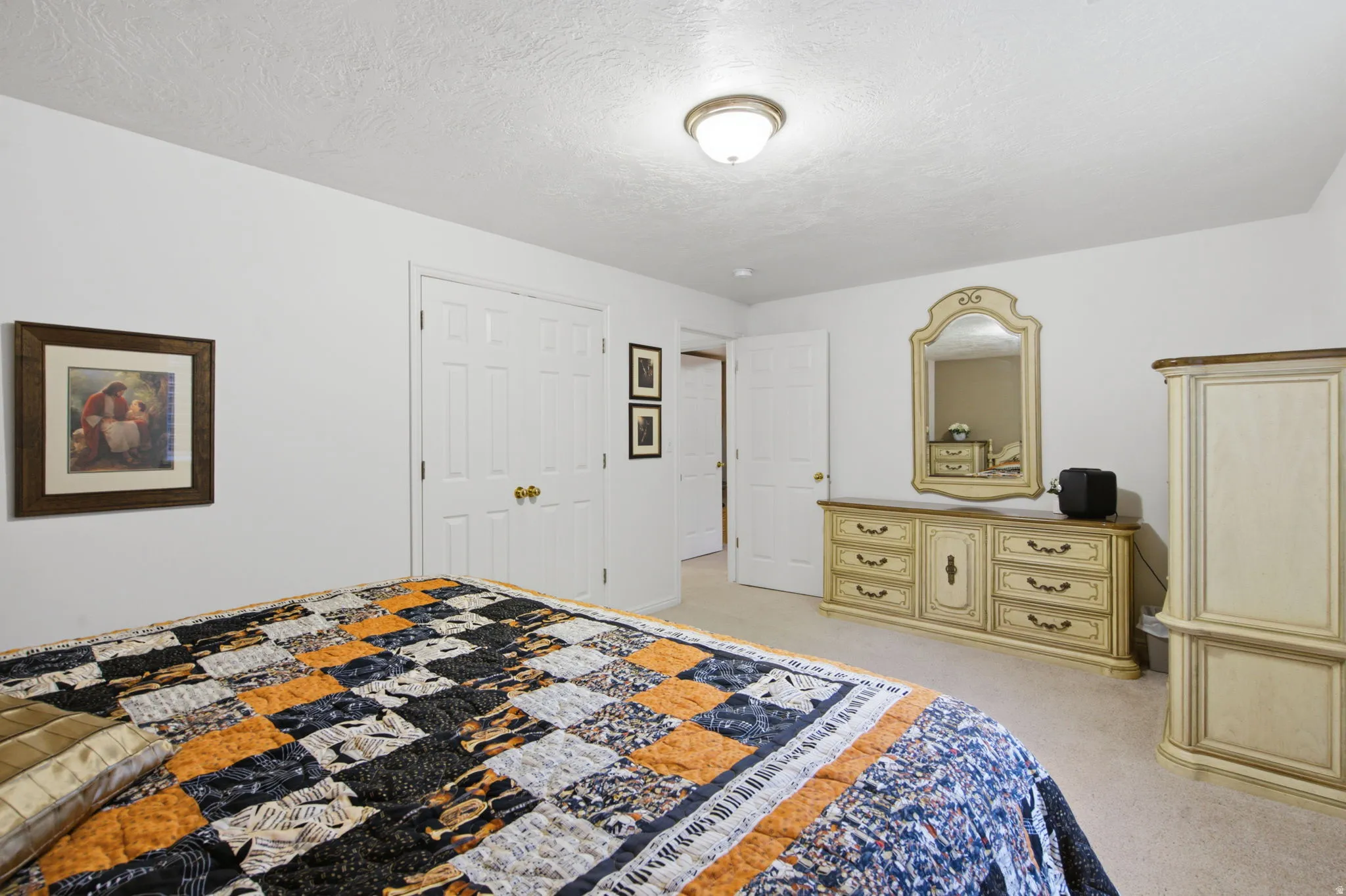 Light-colored carpeting and white walls define this room, featuring a double-door closet with brass hardware