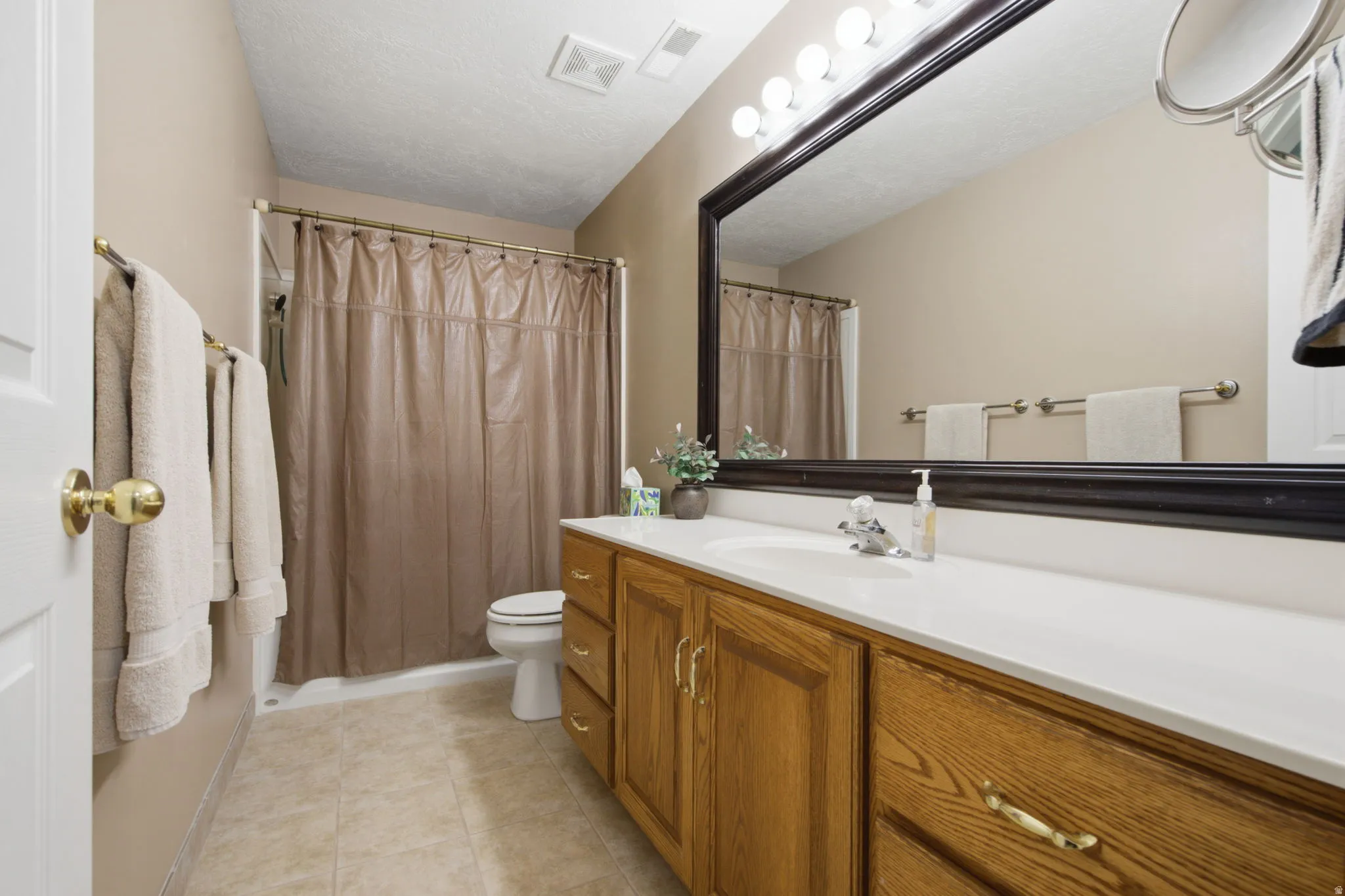 Bathroom featuring a wood-finish vanity with a white countertop and integrated sink