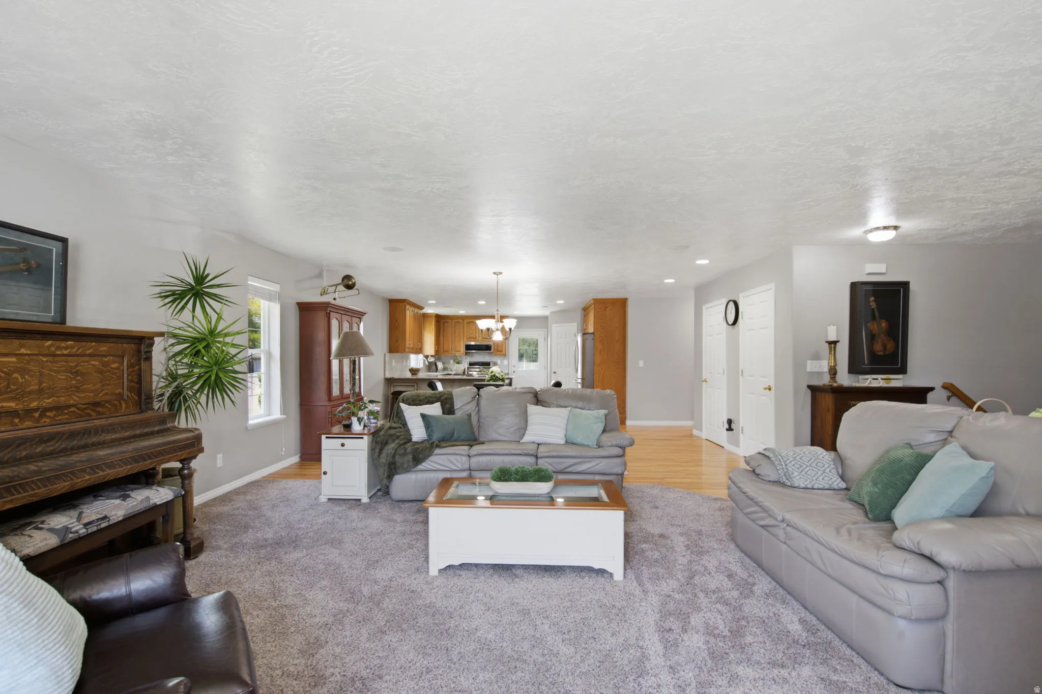 Spacious living area featuring light gray walls, textured white ceilings, and recessed lighting