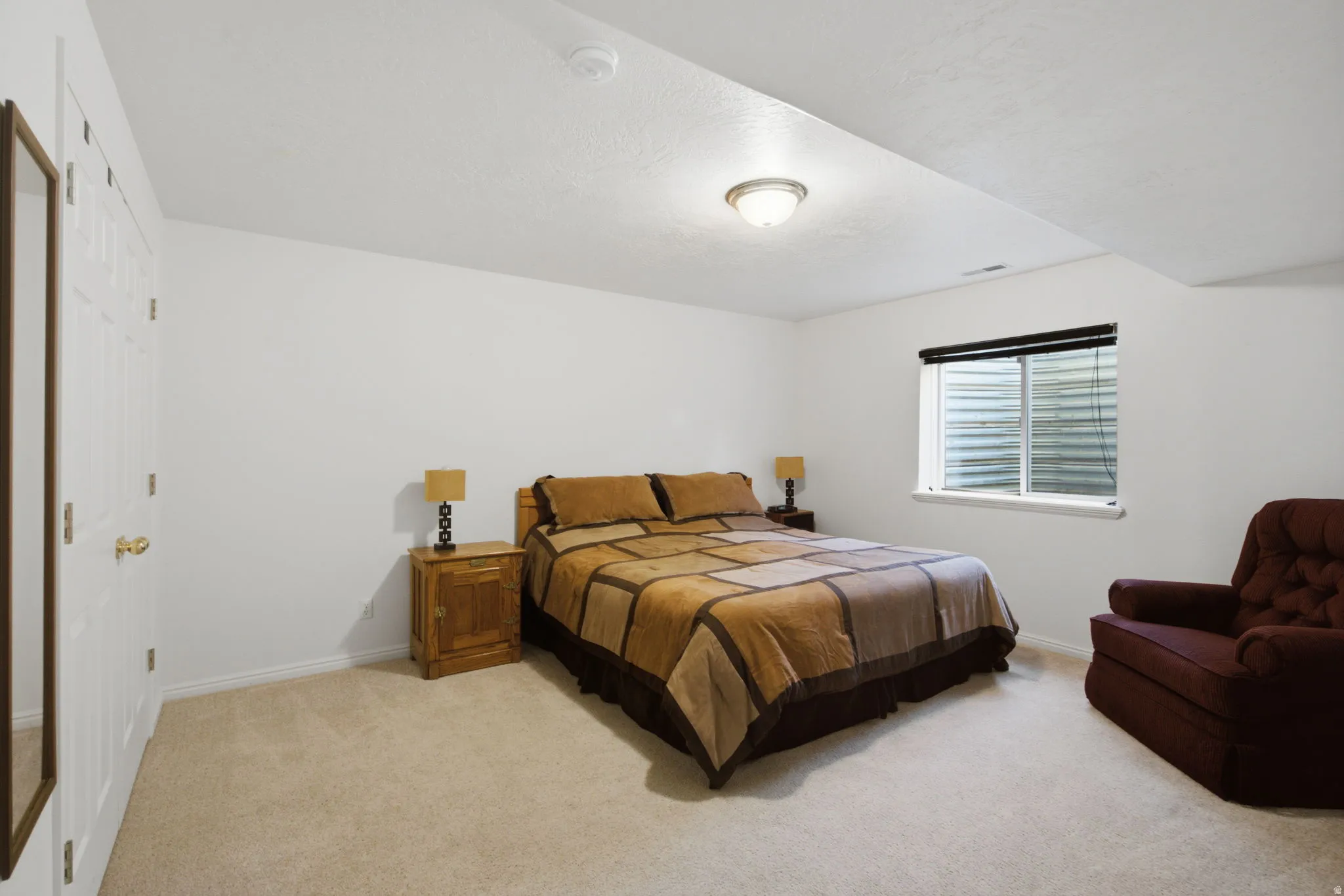 Carpeted room featuring a white paneled door, a single window with blinds, and recessed lighting