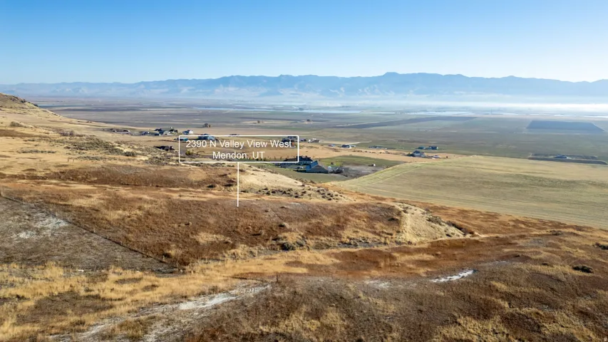 Expansive rural property with mountain range backdrop and distant agricultural fields