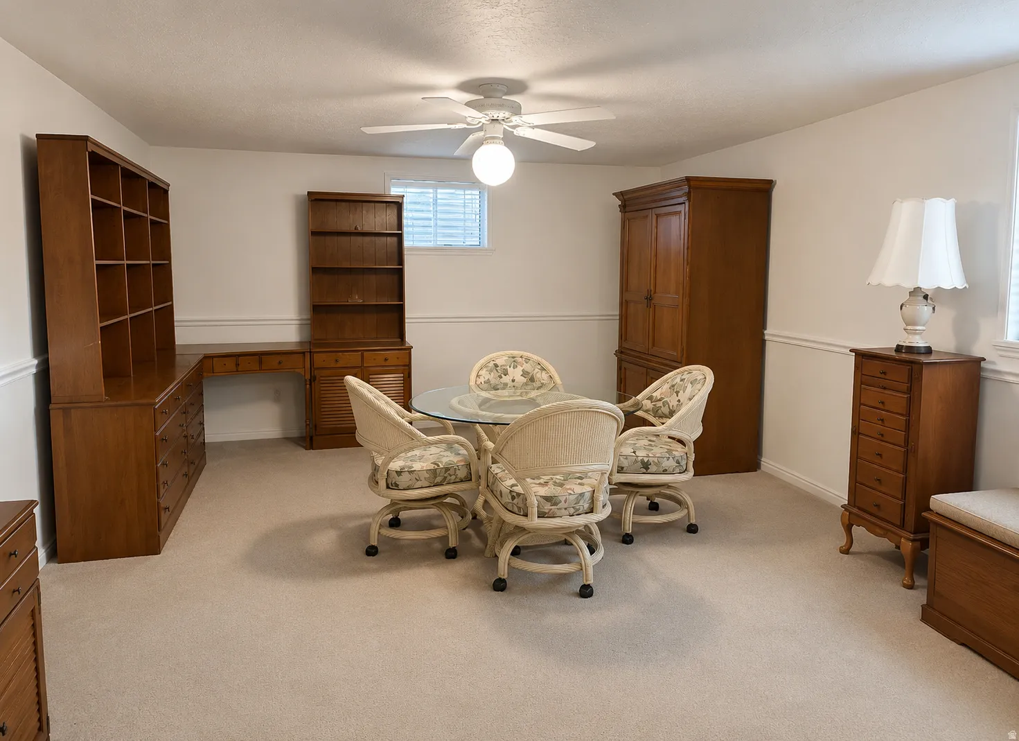 Carpeted room featuring a ceiling fan, a built-in desk with shelving, and a small window with blinds