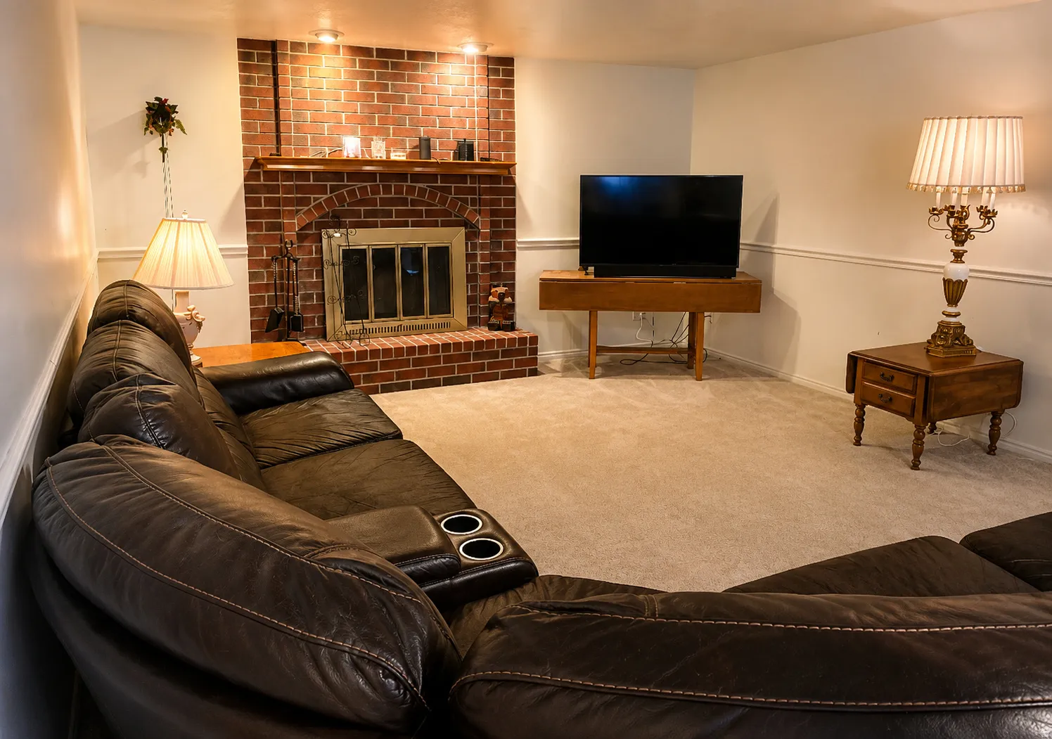 Living area featuring a brick fireplace  a wood mantel, and overhead lighting