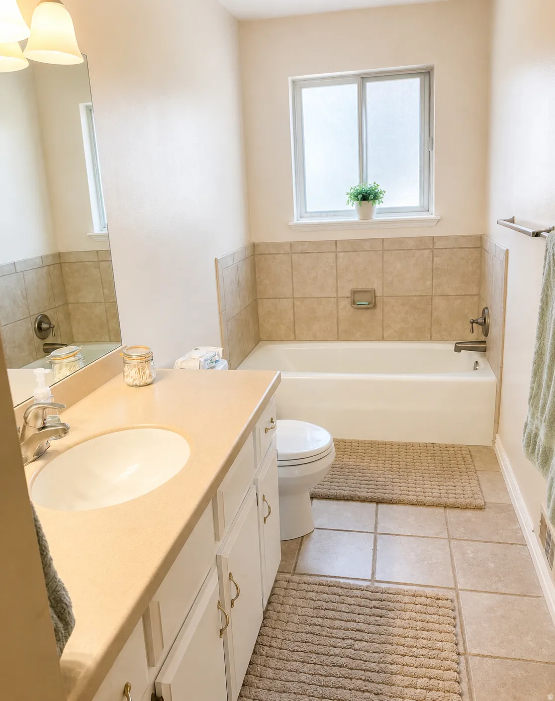 Bathroom featuring a white vanity with an integrated sink, cream-toned countertop, and white cabinetry with brass-finish hardware