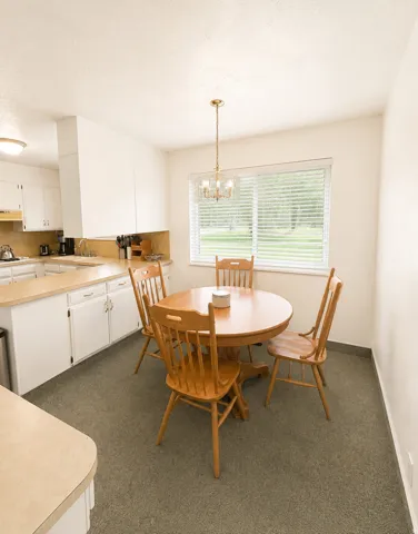Kitchen eating area with a large window, brass chandelier, and light-colored countertops
