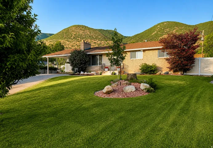 Brick ranch-style residence featuring a carport, established landscaping, and a fenced side yard