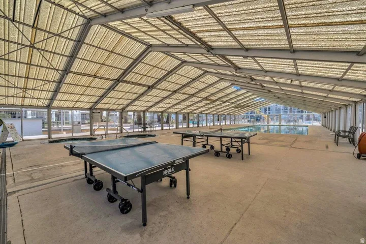 Spacious covered recreation area featuring a large swimming pool, two integrated hot tubs, and a translucent vaulted ceiling