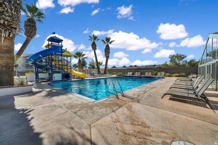 Swimming pool featuring a multi-level water slide structure, surrounding concrete decking, and mature palm trees