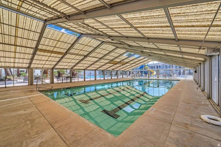 Covered swimming pool with lane markers, integrated handrails, and surrounding concrete decking