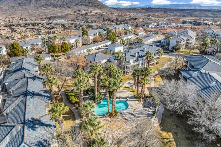 Community pool with surrounding palm trees, green spaces, and multiple residential buildings featuring balconies