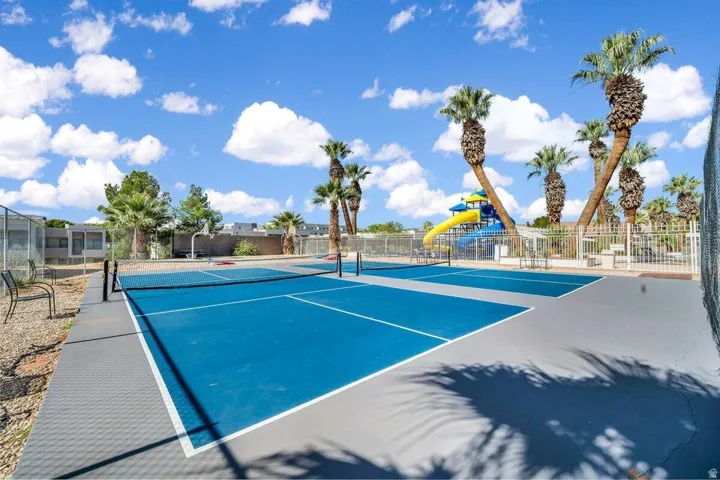 Dual recreational courts with blue surfacing, surrounded by mature palm trees
