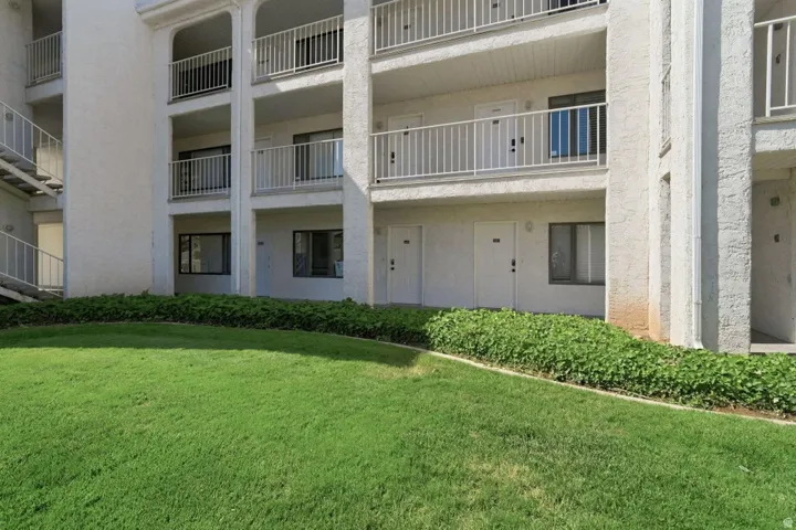 Multi-story building exterior with white stucco finish and individual balconies featuring white metal railings