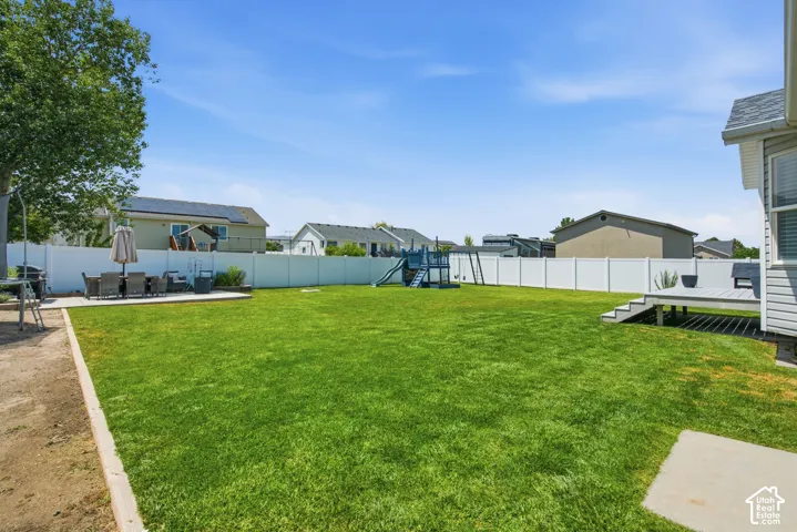 Expansive grassy yard with a white privacy fence