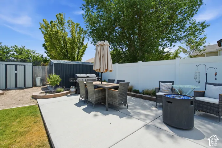 Expansive concrete patio area featuring a white privacy fence, two storage sheds