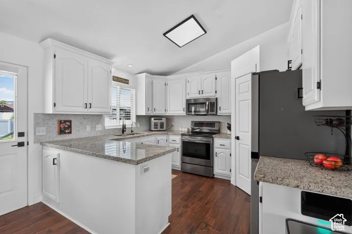 Kitchen featuring white cabinetry, granite countertops, stainless steel appliances, wood-finish flooring