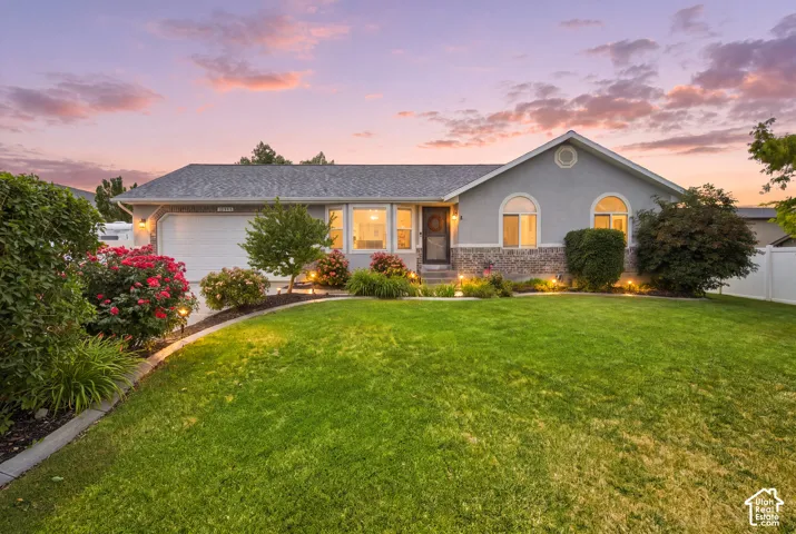 Ranch-style residence featuring a stucco and stone facade, arched windows, and an attached two-car garage