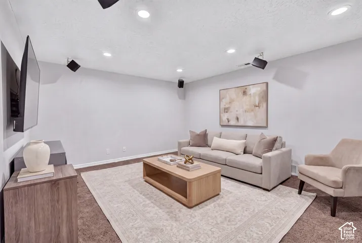 Recessed ceiling lighting illuminates this versatile room, featuring light gray walls, brown carpet, and white baseboards