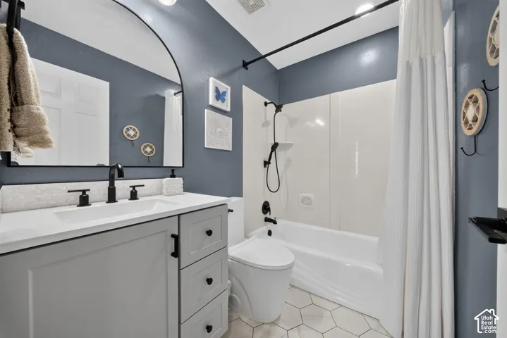 Bathroom featuring a light gray vanity with black hardware, white countertop, and a black-framed arched mirror