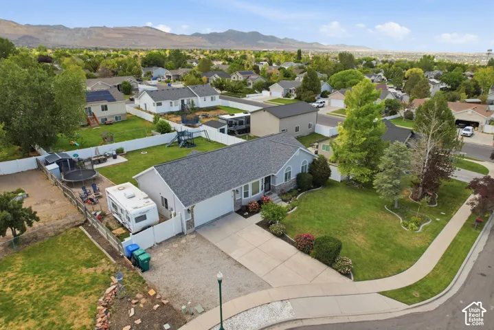 Single-story residence featuring a gray shingle roof, light blue siding with stone accents, an attached garage, and a concrete driveway