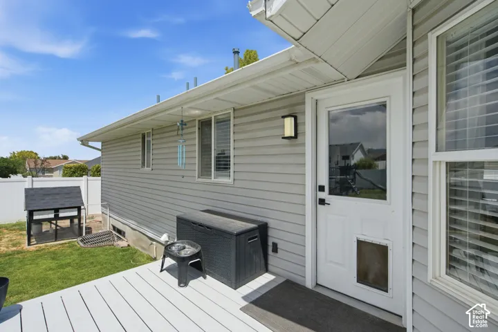 Rear exterior featuring light grey siding, a white deck, and a full-light panel door with integrated pet access