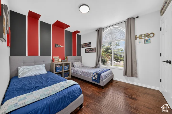 Wood-finish flooring throughout, featuring a bright arched window with blinds, and white baseboards