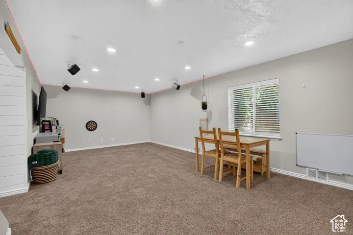 Carpeted open-concept room featuring recessed lighting, a window with horizontal blinds, and accent wall paneling