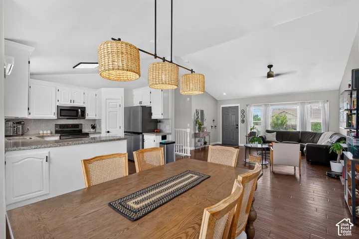 Open concept living space featuring a dining area with a wood-finish table, a kitchen with white cabinetry and light-toned countertops, and a living room with wood-finish flooring