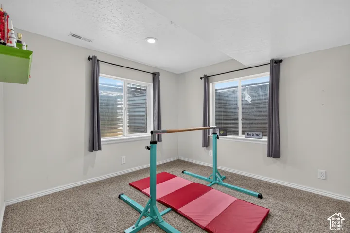 Carpeted room featuring two egress windows with horizontal blinds and recessed lighting