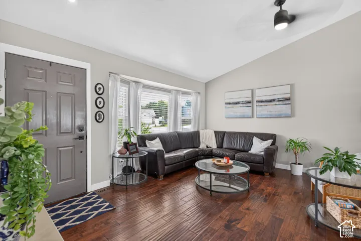 Spacious living area featuring wood-finish flooring, a vaulted ceiling, and a prominent bay window