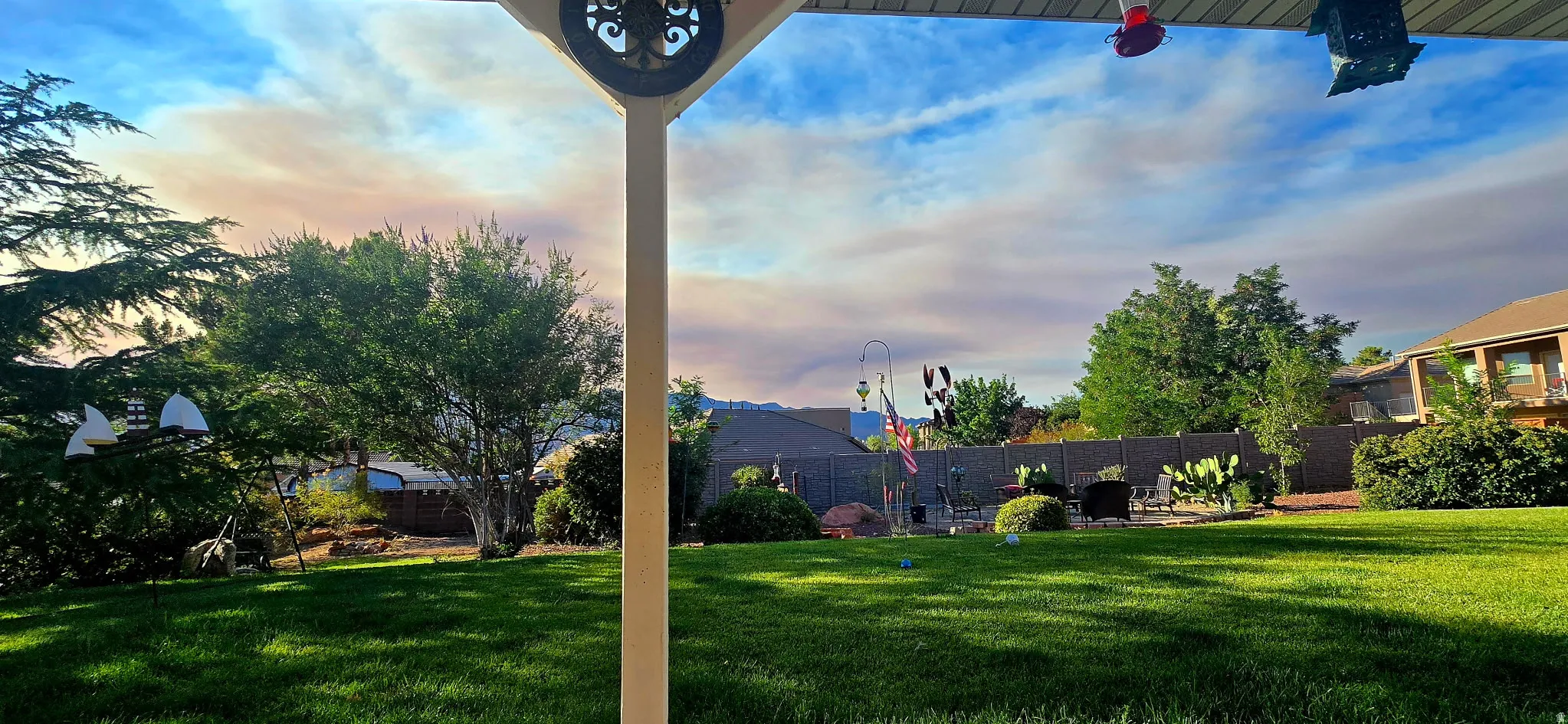 Expansive backyard featuring a manicured lawn, mature trees, and privacy fencing