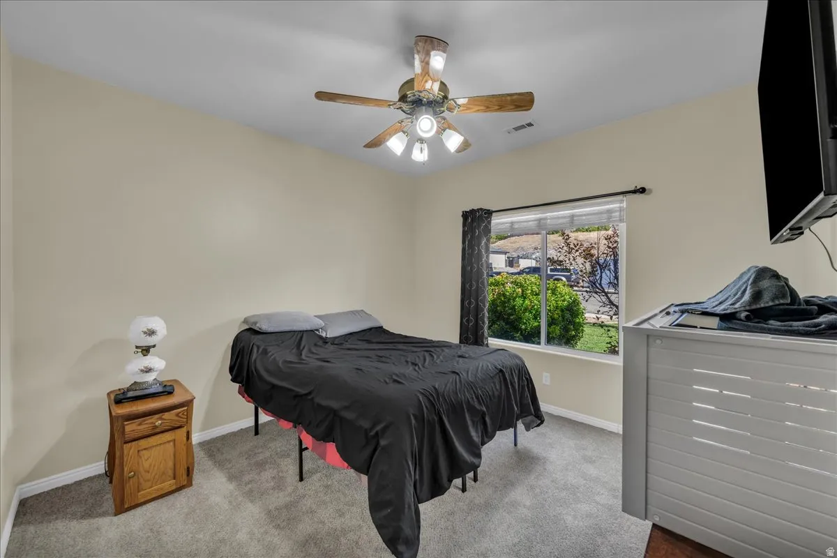 Carpeted room with a ceiling fan light fixture