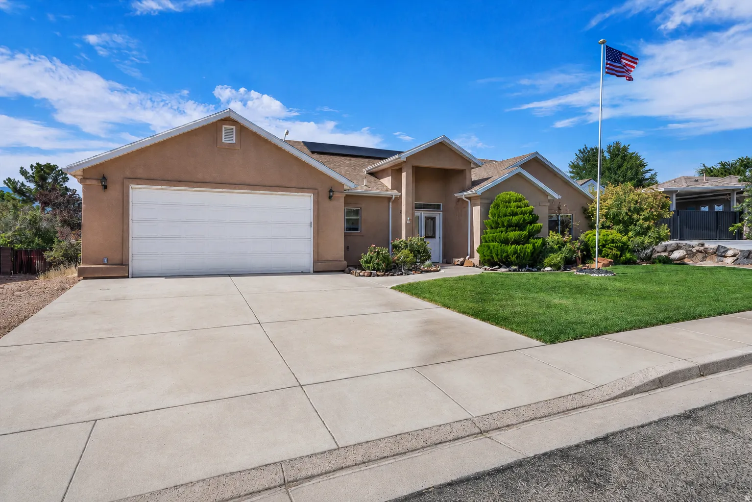 Stucco exterior residence featuring a two-car garage, concrete driveway, and a covered entry