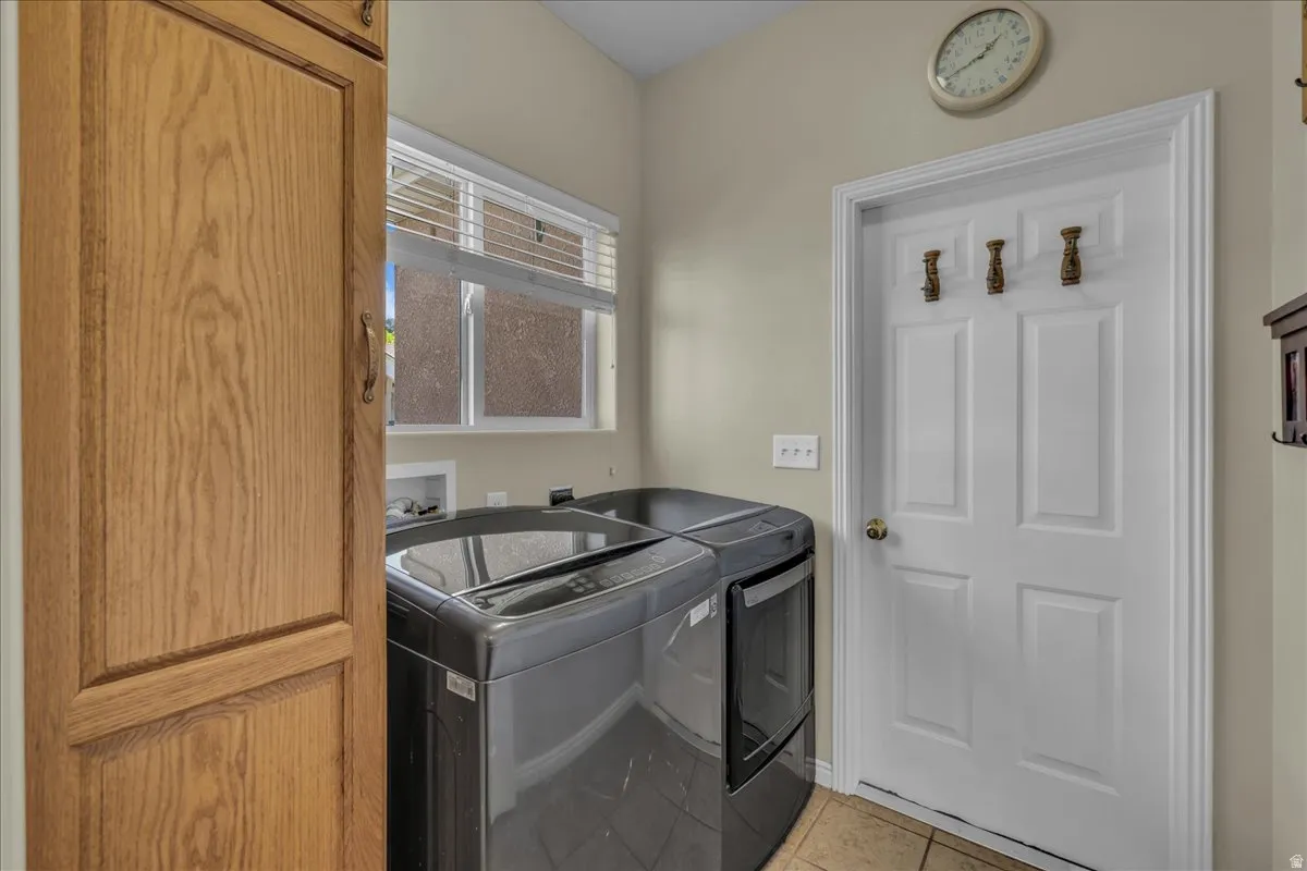 Dedicated laundry space featuring a window, built-in wooden cabinetry, and tile flooring