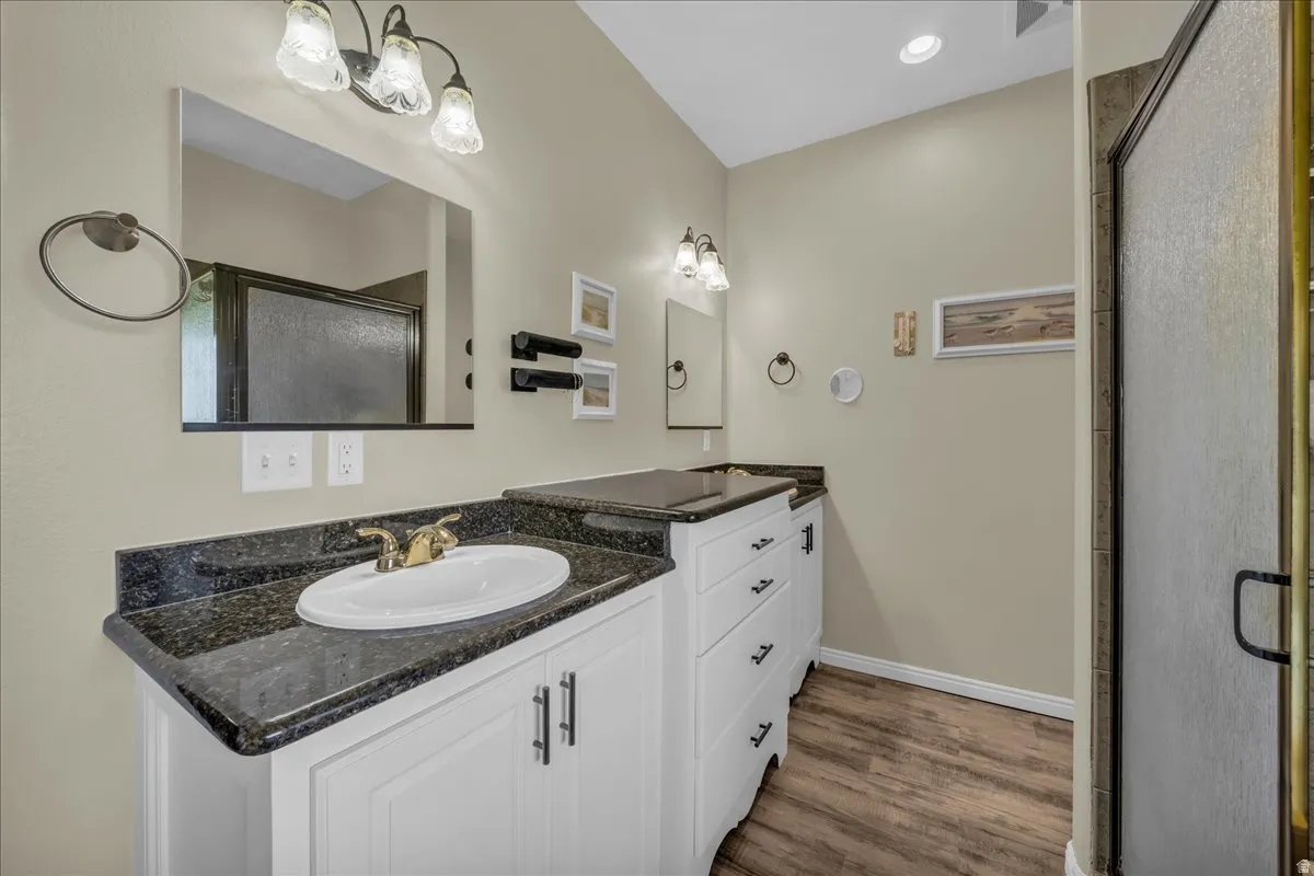Bathroom featuring a white vanity with dark stone-finish countertops, an undermount sink with a brass-finish faucet, and a large mirror