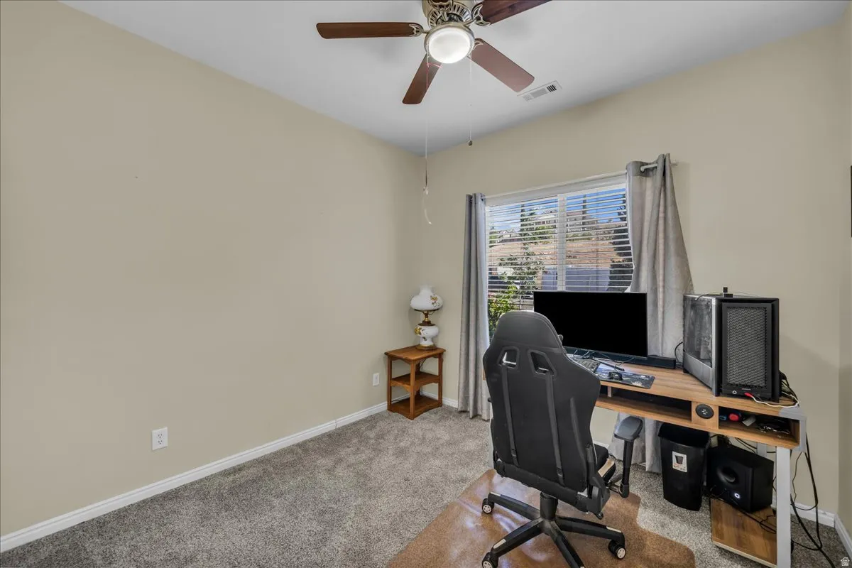 Carpeted room featuring a ceiling fan with integrated lighting, a window with horizontal blinds and drapes, and neutral wall paint