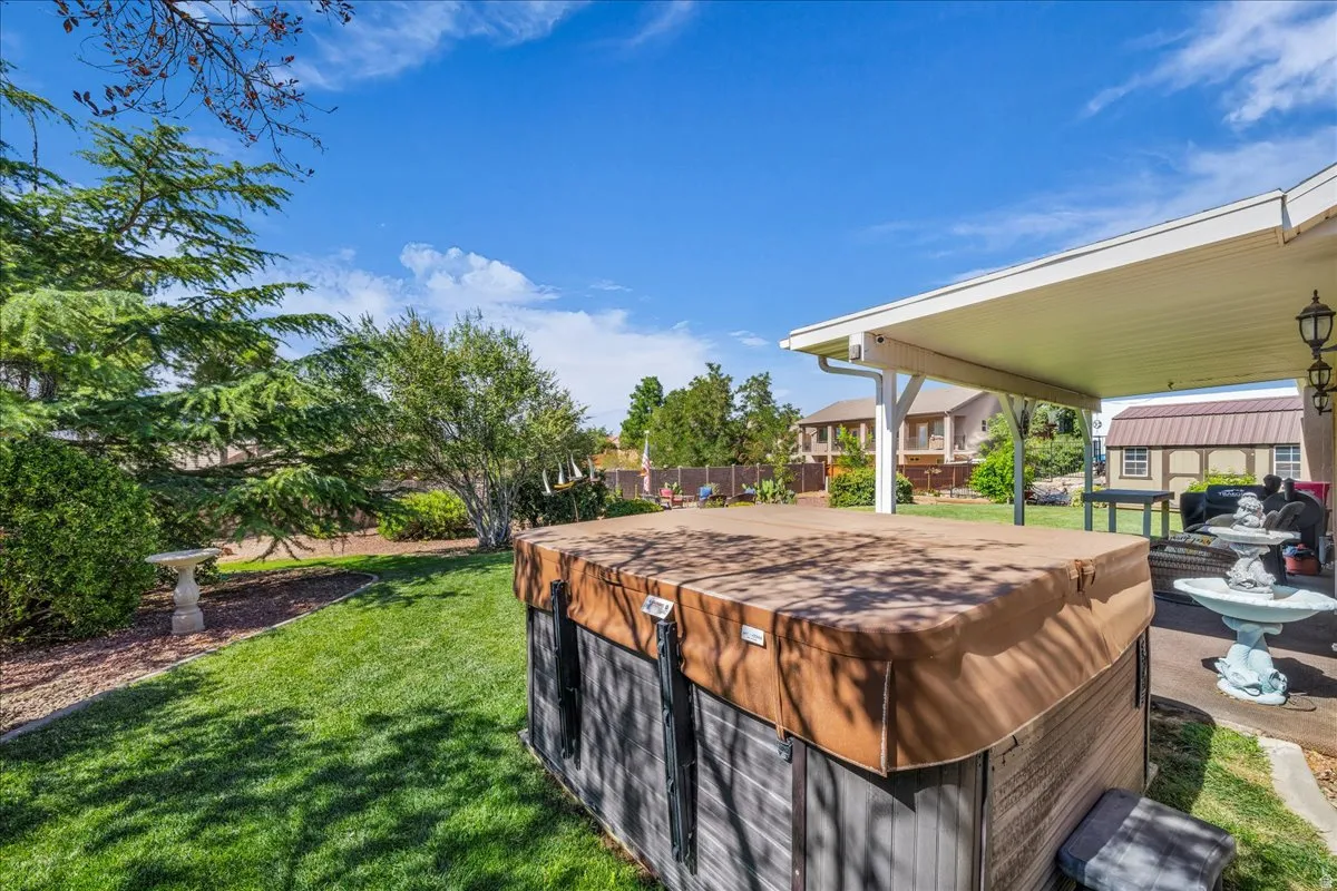Expansive backyard featuring a covered patio, a spa, and a manicured lawn