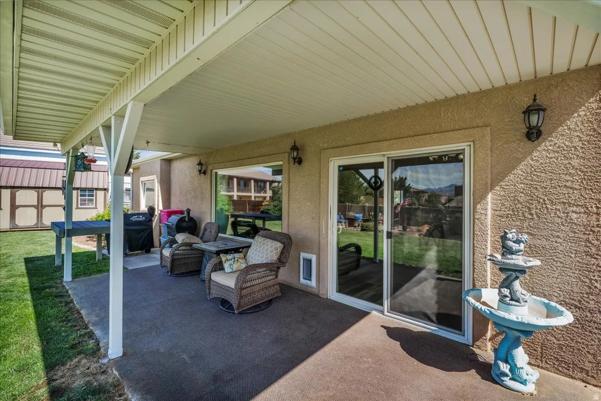 Covered patio with textured concrete flooring, stucco exterior, and a sliding glass door