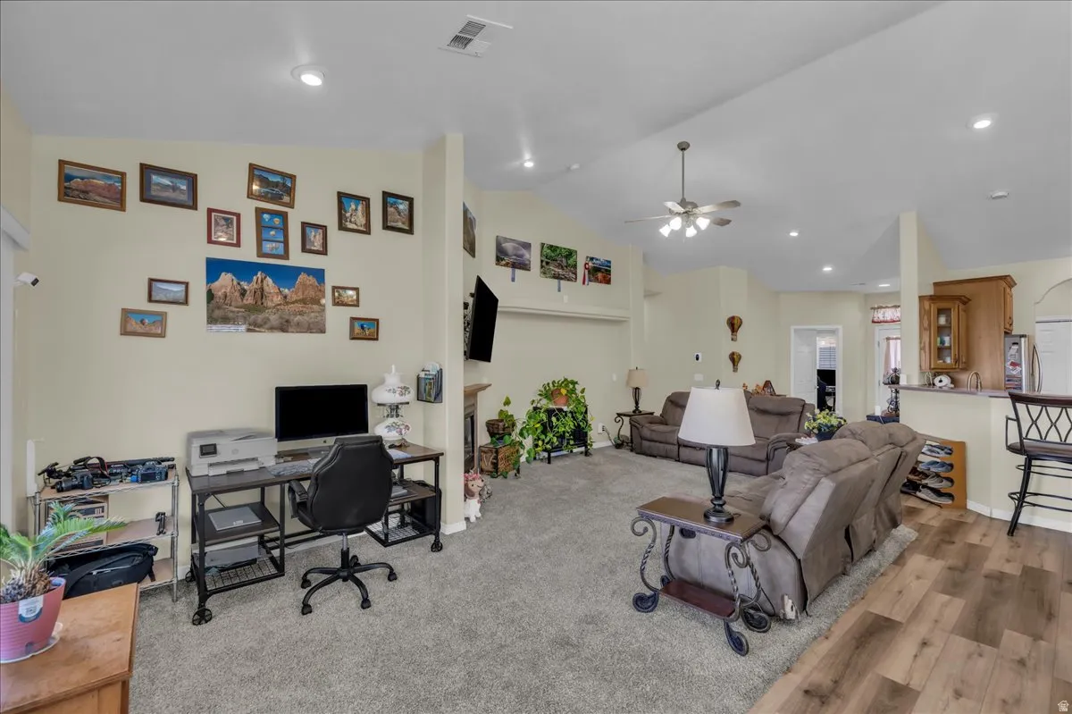 Open-concept living area featuring a vaulted ceiling and a ceiling fan with integrated lighting