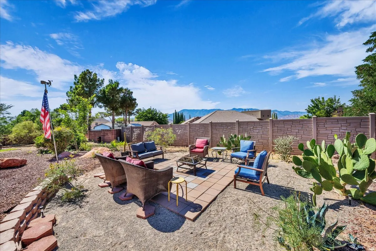 Spacious backyard featuring a paver patio, a perimeter block wall, desert landscaping with cacti, and distant mountain scenery