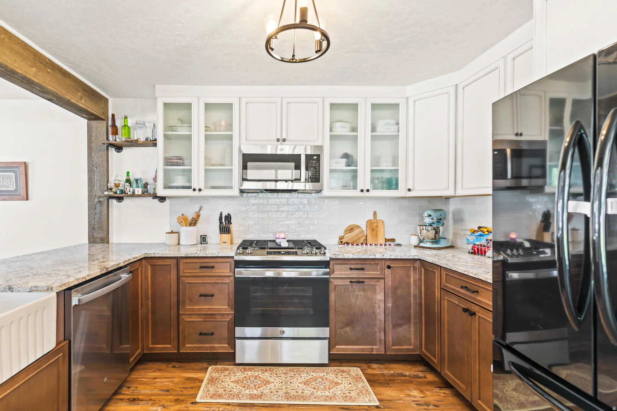 Kitchen featuring wood-finish flooring, two-tone cabinetry with white upper and wood-tone lower cabinets, granite countertops, and stainless steel appliances
