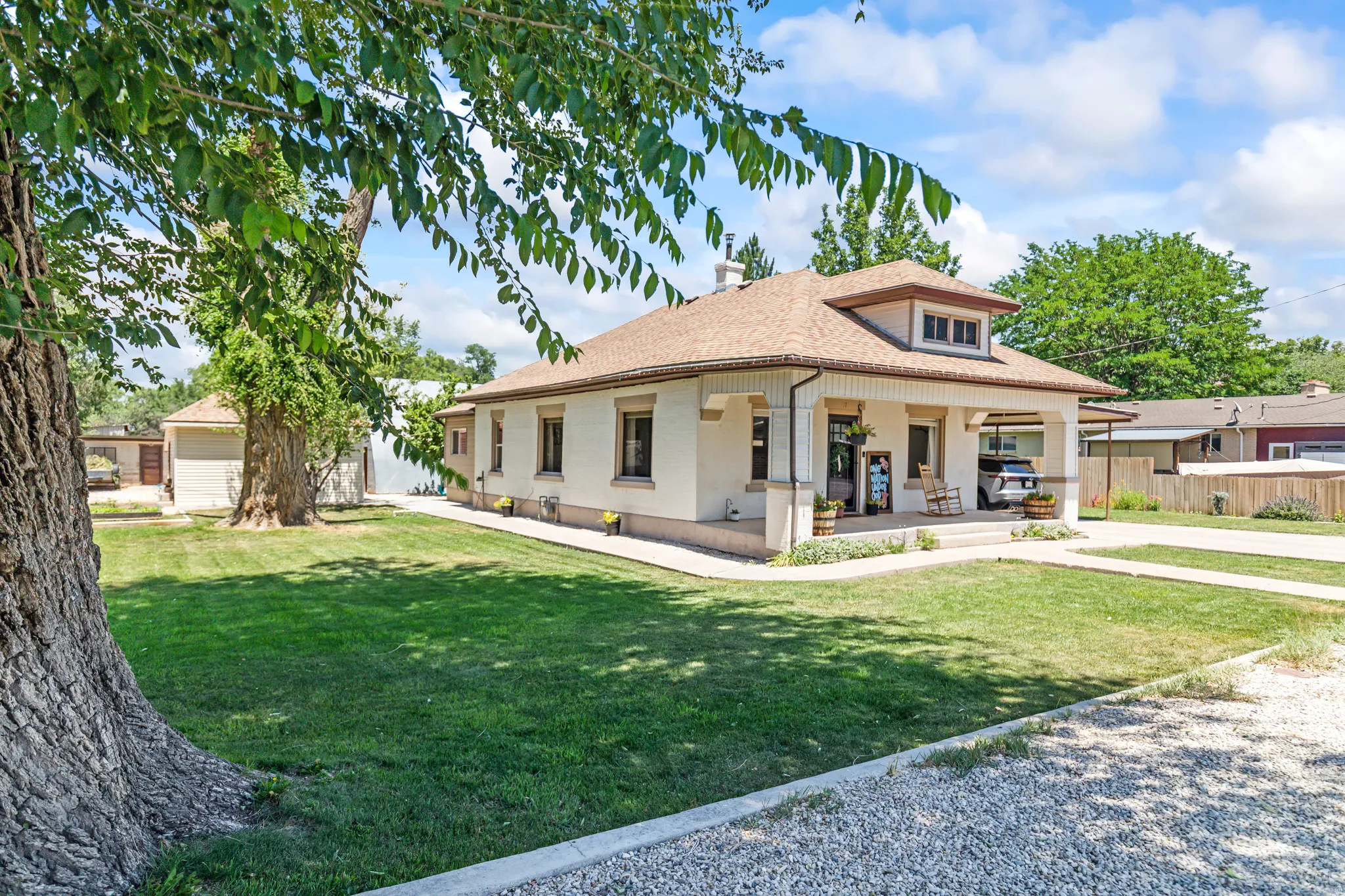 Traditional-style single-story residence with a covered front porch featuring columns, a dormer window, and a light-toned exterior