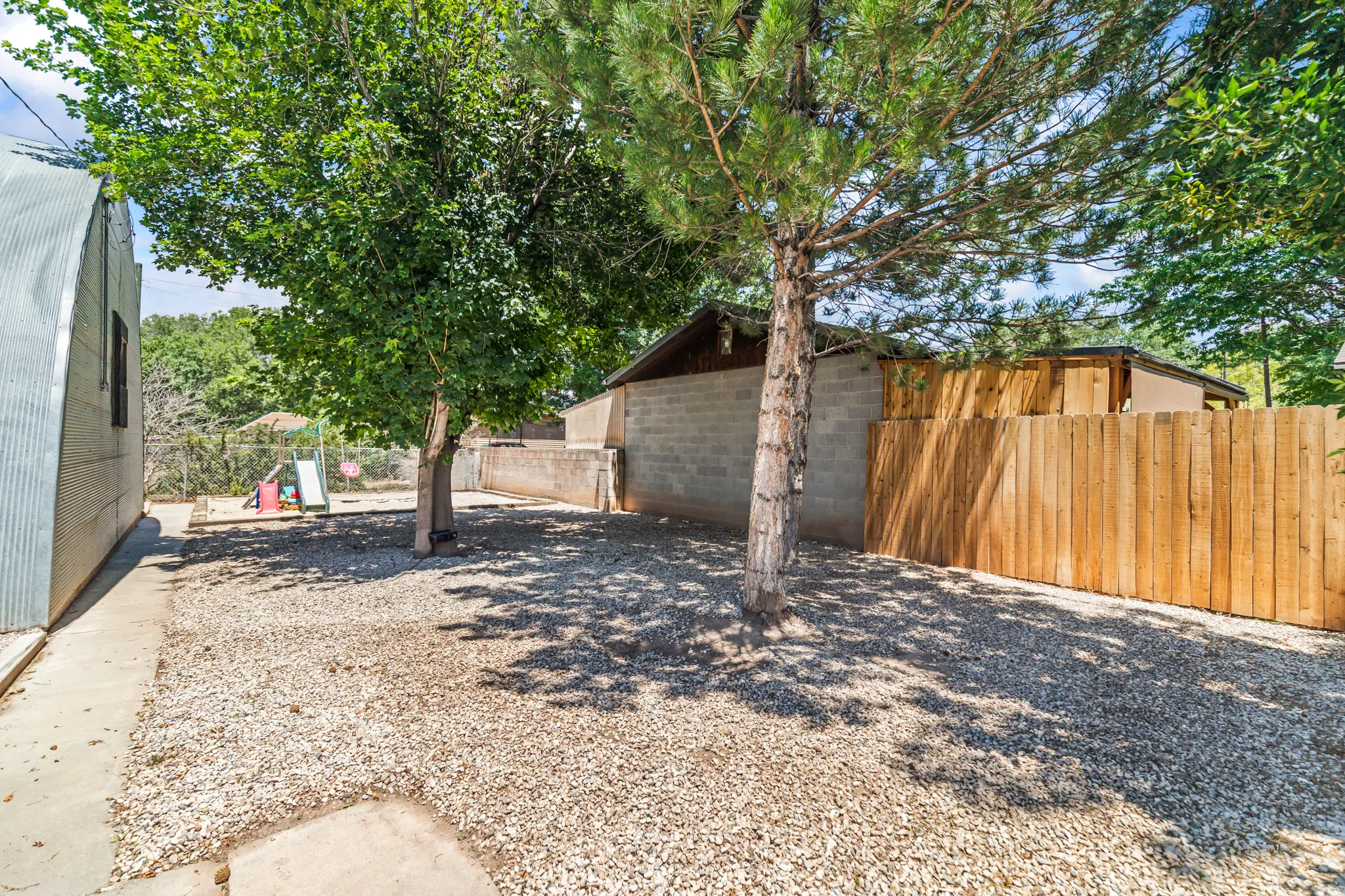 Gravel-covered yard with mature trees providing natural shade